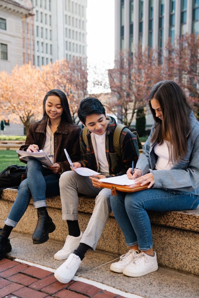 pexels photo 7973199 7973199 A group of young students studying together on a sunny day in an urban setting.